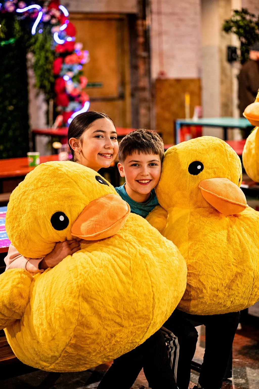two children in Fayre Play with large stuffed duck prizes